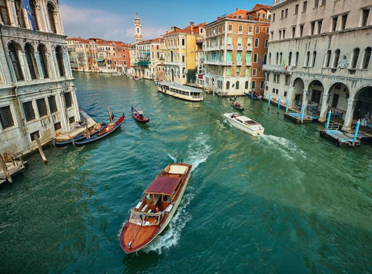 Venetian canal scene bustling with boats, showcasing vibrant architecture under a clear blue sky, capturing the essence of Venice.