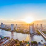 Stunning sunset over Bangkok's skyline, with the Chao Phraya River reflecting vibrant colors and modern skyscrapers.