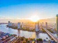 Stunning sunset over Bangkok's skyline, with the Chao Phraya River reflecting vibrant colors and modern skyscrapers.