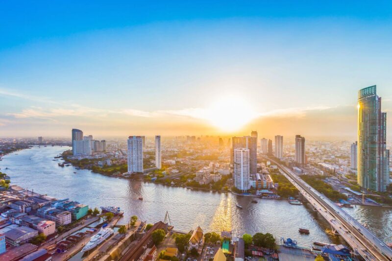 Stunning sunset over Bangkok's skyline, with the Chao Phraya River reflecting vibrant colors and modern skyscrapers.