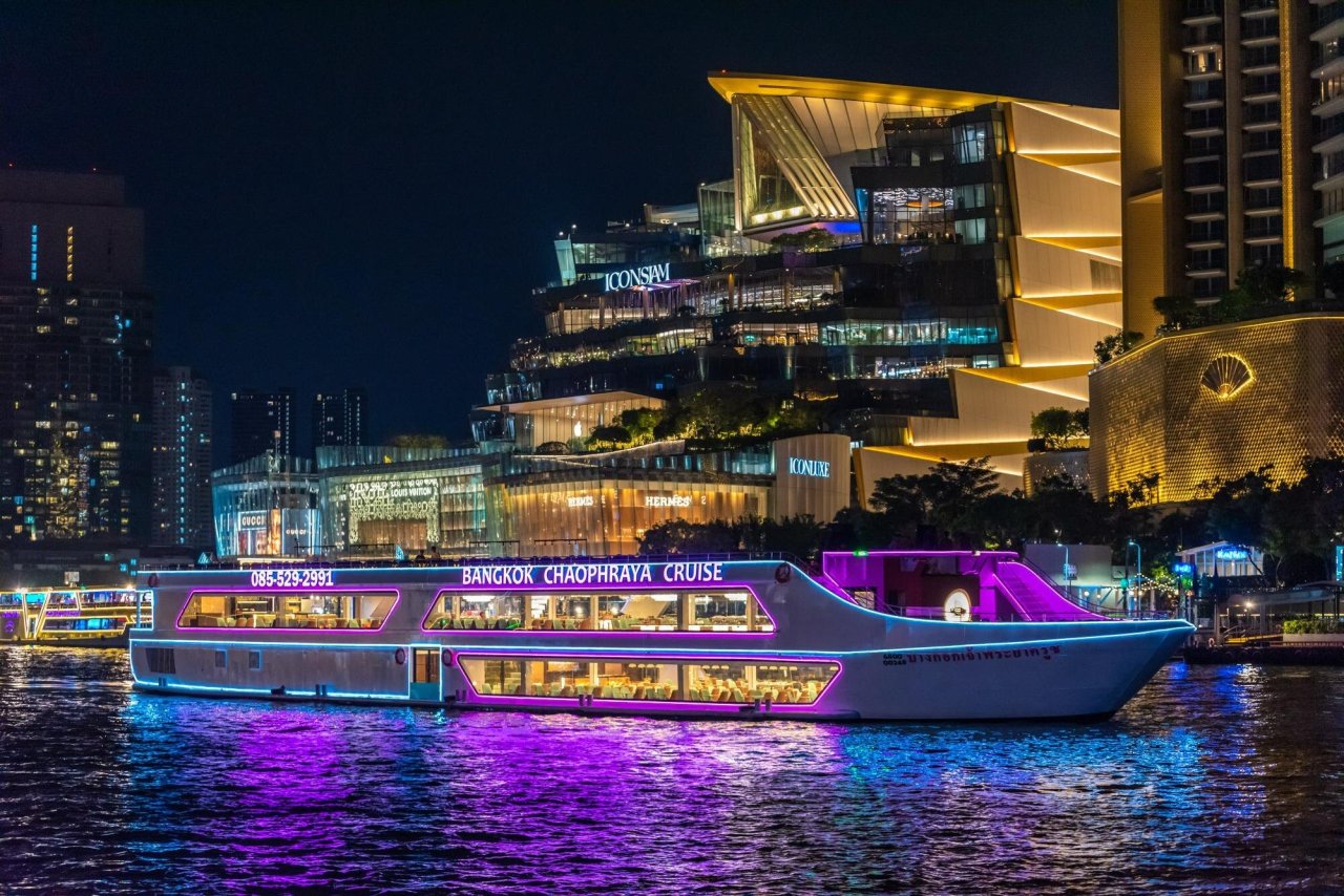 Bangkok Chao Phraya cruise boat illuminated at night, offering scenic views along the river and vibrant city skyline.