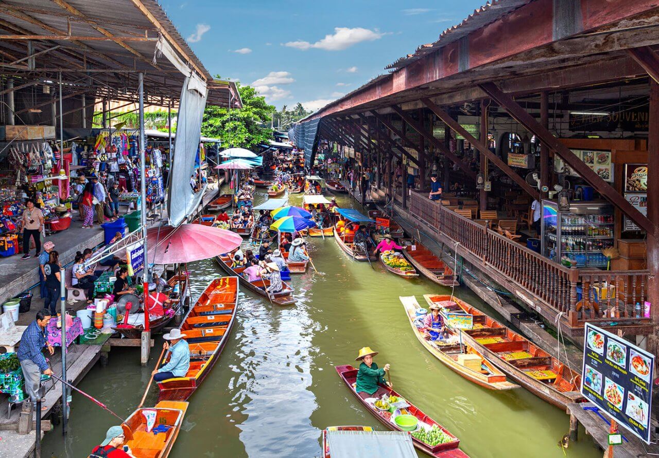 Colorful floating market bustling with activity, showcasing vendors and shoppers in traditional boats along a scenic waterway.