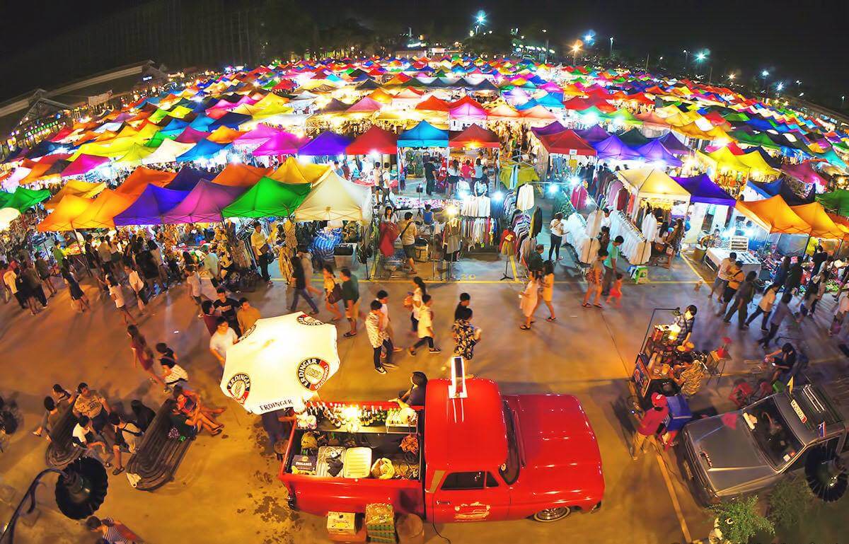 Vibrant night market scene with colorful tents, bustling crowds, and food vendors creating a lively atmosphere.