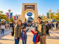 Family enjoying a fun day at Universal Studios Japan, posing in front of the iconic entrance with colorful decorations.