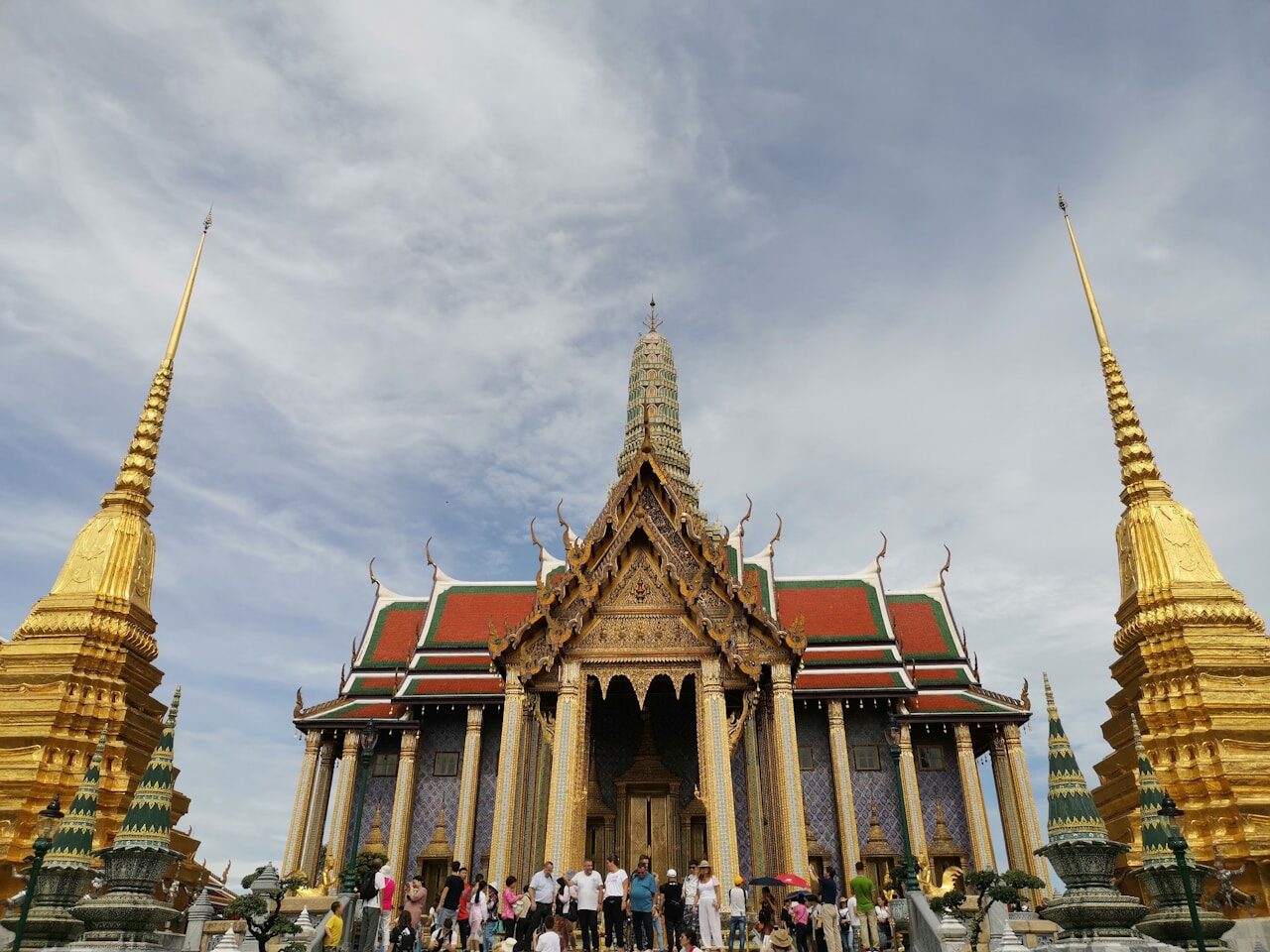 Grand Palace in Bangkok features stunning golden spires and intricate architecture, attracting numerous tourists daily.
