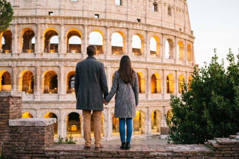 Couple admiring the illuminated Colosseum at sunset, showcasing romantic moments in historic Rome.